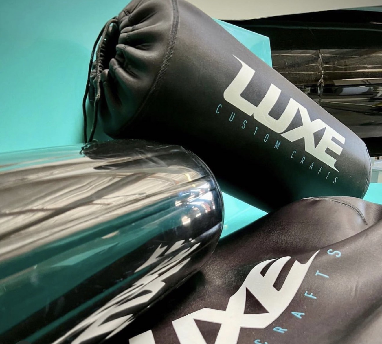 Luxe Custom Crafts branded black neoprene FenderSox against teal hull