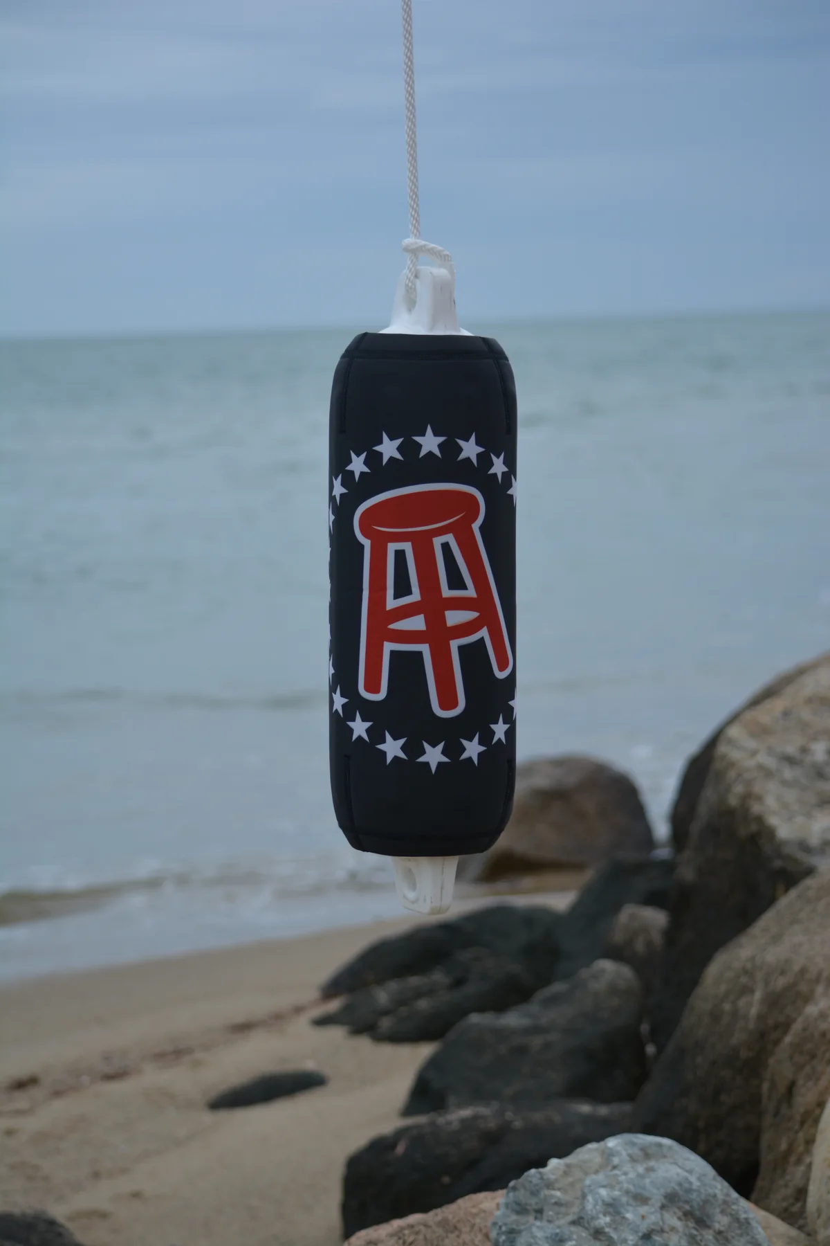Barstool Sports custom FenderSox suspended above a rocky beach