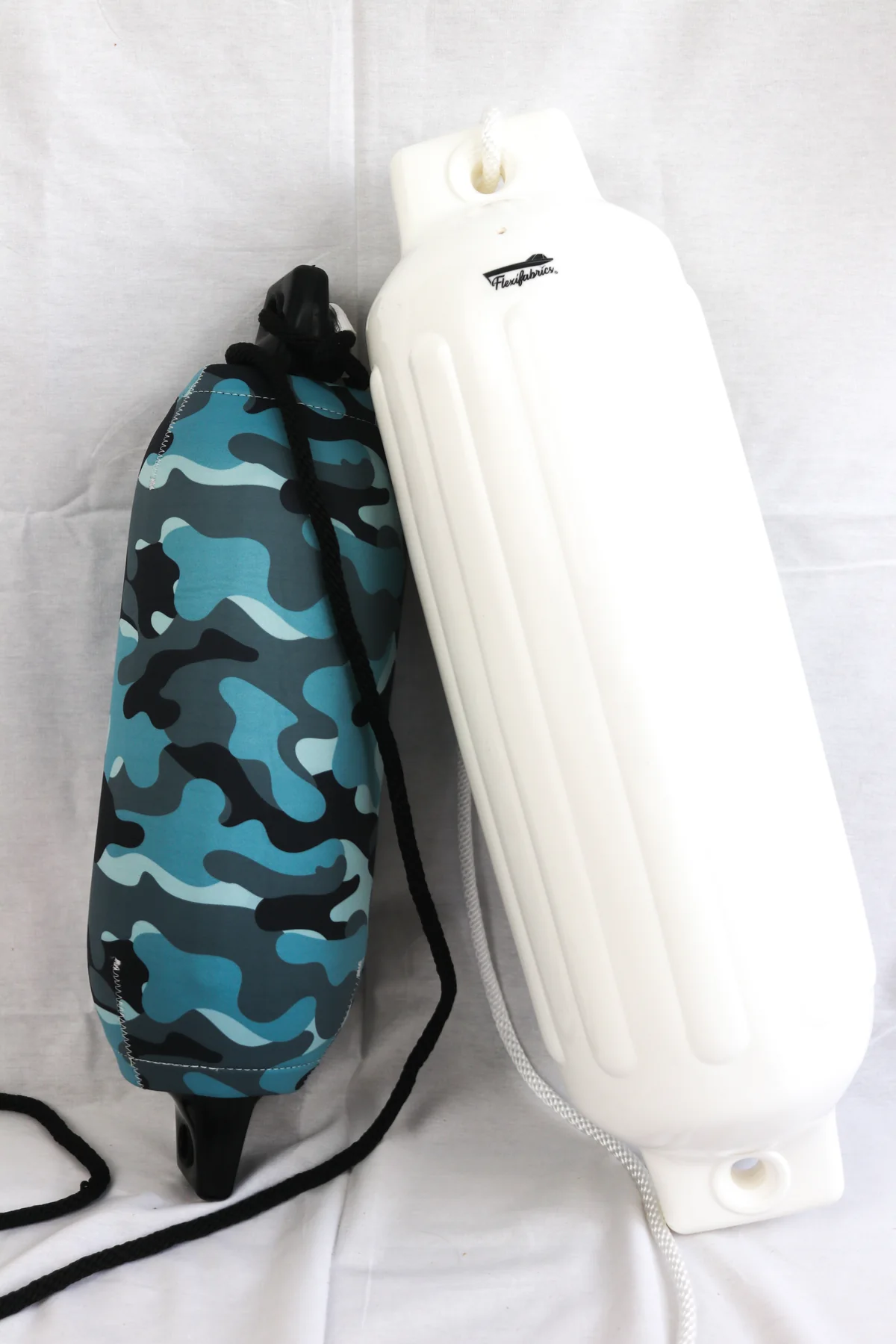 Blue camouflage neoprene FenderSox displayed beside the uncovered white boat fender it fits