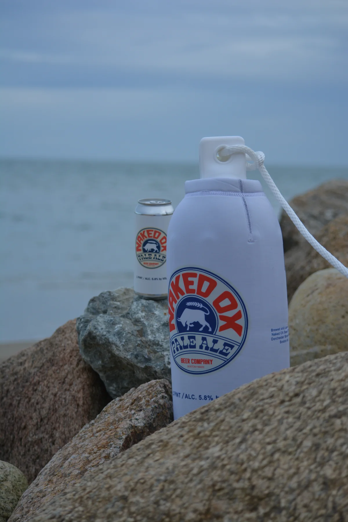 Naked Ox Pale Ale branded custom FenderSox displayed on coastal rocks